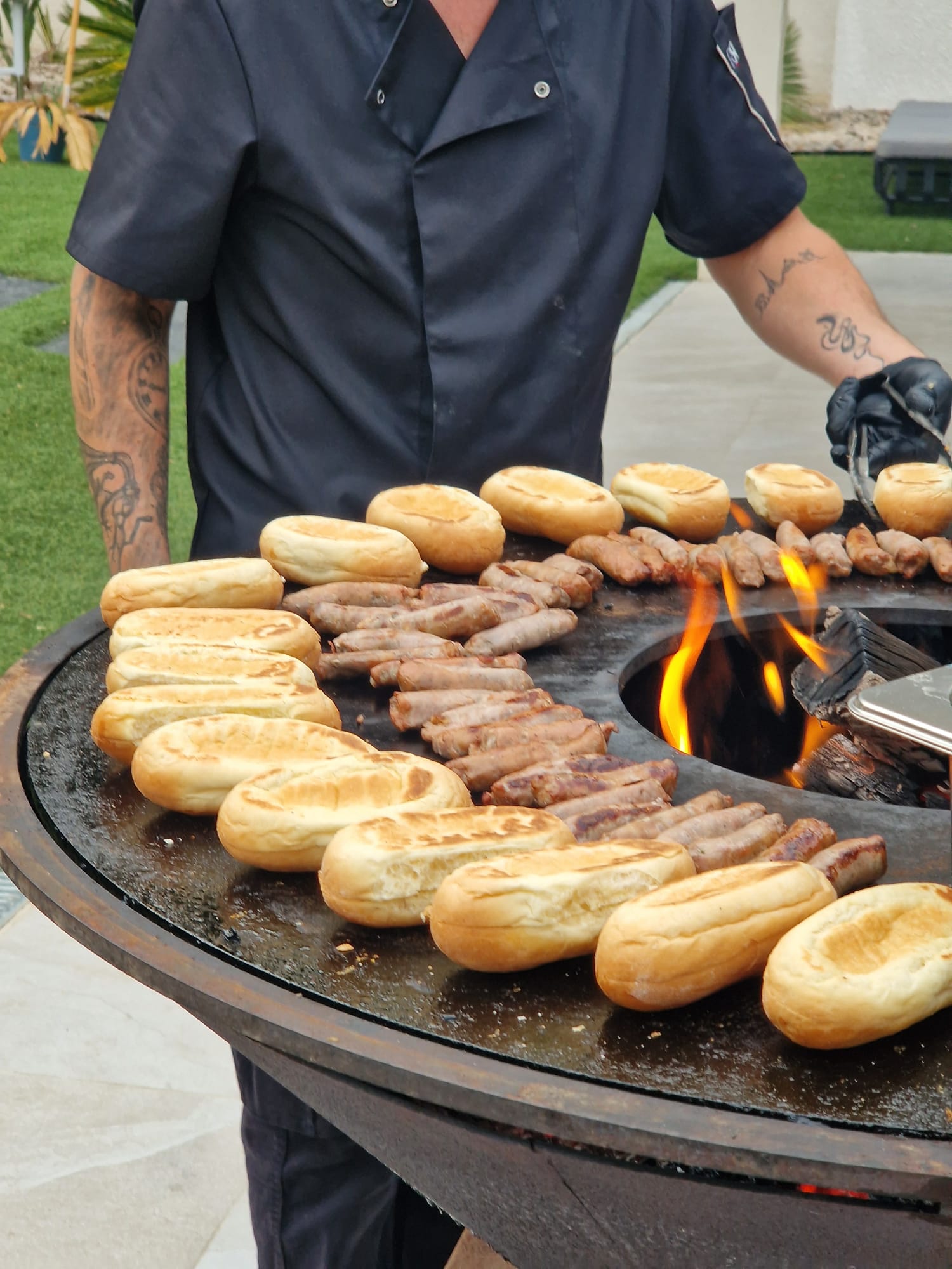 Saucisses et pains grillés sur la plancha du brasero